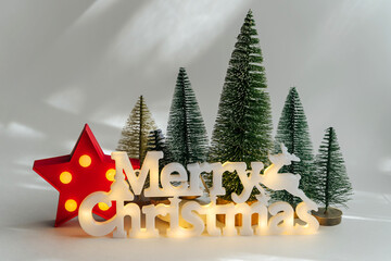 Wall Mural - Merry Christmas! Miniature  Christmas tree with shiny lettering. Winter cute landscape. Cozy small world. Christmas decorations, holiday concept.