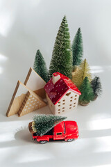 Canvas Print - Miniature house and fir trees with red car with Christmas Tree on white background. Winter cute landscape. Cozy small world. Christmas decorations, holiday concept.