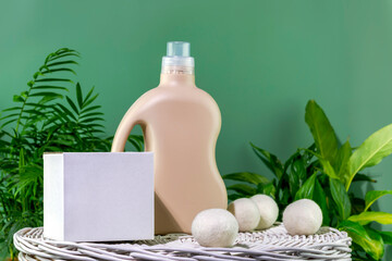 Natural laundry detergent mockup. Bottle of washing gel or fabric softener and box with detergent powder on white laundry basket on a green background with green leaves. Front view