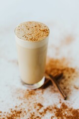 Sticker - Closeup shot of a glass of a cinnamon mocha shake, surrounded with cinnamon sticks and powder