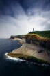 Beautiful scene of Faro Cabo Mayor lighthouse on rocky cliff Santander city, Spain under gray sky