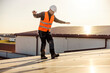 Laborer in protective uniform walking carefully on the roof with solar panels.