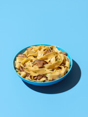 Wall Mural - Pasta with wild mushrooms minimalist on a blue background