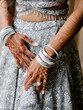 Indian woman bride in a silver bright wedding dress, with luxury beads and silver accessories on her hands