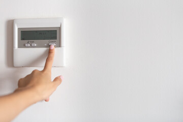 Close-up of a young woman's hand pressing the on/off button of the air conditioner or heater