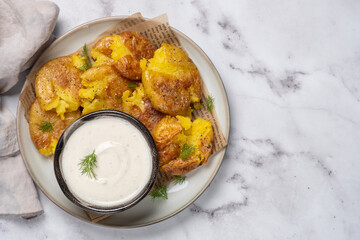 Wall Mural - smashed potato on parchment paper with garlic sauce