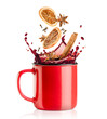 a splash of mulled wine, falling into a red mug of cinnamon, cloves, dried orange and anise on a white isolated background