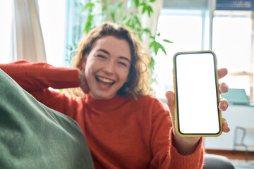Happy young woman holding mobile phone in hand showing cellphone display, presenting big white blank cellular display template mock up, smartphone mockup screen for digital application promo ads.