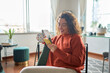 © insta_photos - Young smiling pretty woman holding smartphone technology drinking tea or coffee relaxing at home. Happy positive lady enjoying using mobile cell phone having fun while buying in ecommerce shop.