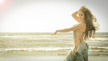 A Bellydance Dancer Dancing To Arabic Music In Front Of A Beach