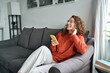 © insta_photos - Young happy woman using mobile cell phone sitting on couch at home. Smiling cheerful lady laughing holding smartphone having fun while buying in ecommerce shop or watching funny videos online.