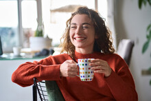 Young Smiling Pretty Woman Holding Cup Drinking Warm Tea Or Coffee Relaxing Dreaming At Home. Happy Positive Lady Enjoying Hot Drink Daydreaming With Mug In Hands In Cold Cozy Winter Weekend Morning.