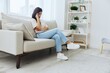 © SHOTPRIME STUDIO - Headache woman sits at home on the couch and touches her head with her hands massage of the temples, high fever in case of illness, migraine
