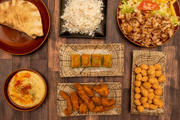 Wall Mural - Set of kebab restaurant food dishes with mixed lamb and chicken meat, croquettes, pilau rice, sweet baklava, chicken puffs, chickpea hummus with poimentos and olive oil