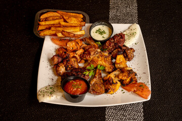 Wall Mural - Plate of grilled meats with vegetables, sauces and homemade chips