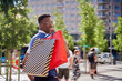 © Oscar - Smiling young african american man carrying shopping bags and looking at camera