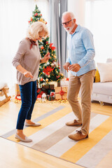 Wall Mural - Senior couple dancing while celebrating Christmas at home