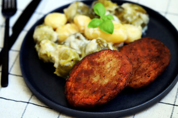 Schnitzels with potatoes and Brussels sprouts in white sauce. A dish of German cuisine.