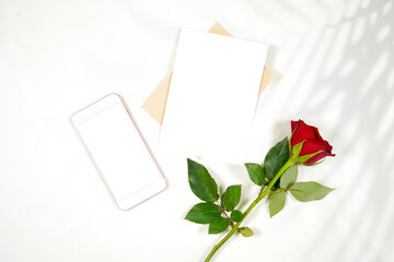 Wall Mural - Greeting card and phone product mockup. Valentine's day wedding birthday love theme, styled with a red rose against a minimalist white background. Boho style fern shadow photography.