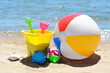 Set of plastic beach toys and inflatable ball on sand near sea