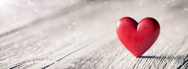 Wall Mural - valentines day - single red wooden heart on white table with sunlight and bokeh