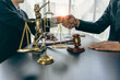 © ArLawKa - Close-up view of lawyer and client holding hands with scales and hammer next to law adviser concept