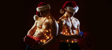 Sexy Male Santa With Strong Six Pack Abshold Gift Christmas Gift On Black Isolated Background. Sexy Muscular Men. Concept Of The Twins. Two Twin Brothers With Bare Naked Body Torso.