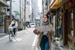 © PR Image Factory - Asian Japanese woman holding consulting a map on the street in Osaka japan. she looks into distance while checking for directions during spring season