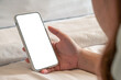 © Nathasa - Close up relax women using a smartphone with an empty white screen lazy on the bed at home.
