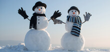 Snowmen Holding Hands Outdoors. Winter Snowman In Black Hat, Scarf And Gloves. Christmas Winter Banner With Snowman. Winter Greeting Card With With Snowman.