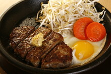 Sliced Steak With Butter, Vegetables And Egg On A Sizzling Plate