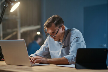 Wall Mural - young employee works on a laptop in the office at night .