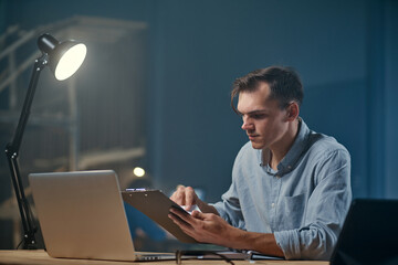 Wall Mural - young businessman works with documents in a night office .