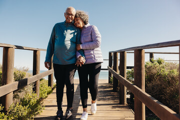 Wall Mural - Elderly couple taking a walk along a foot bridge at the beach