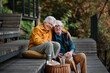 © Halfpoint - Happy senior couple resting near lake after walk and looking at smartphone.