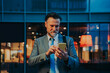 © Westend61 - Mature businessman using smart phone in front of building at night