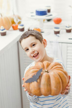Happy Boy Holding Pumpkin Standing At Home