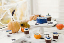 Pumpkins With Cupcakes And Halloween Decoration On Table At Home