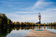 © Westend61 - Woman practicing yoga on jetty at lake