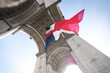 Wide angle photo with the National Flag of France waving under the Arch of Triumph landmark building during Armistice Day.