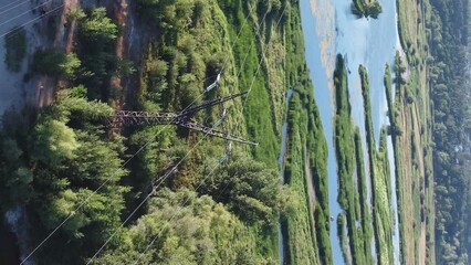 Wall Mural - Aerial view of high-voltage power towers with wires passing through a small river.