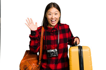 Wall Mural - Traveler asian woman holding a suitcase isolated receiving a pleasant surprise, excited and raising hands.