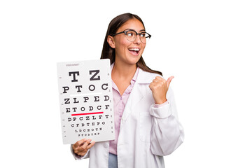 Young caucasian oculist woman isolated points with thumb finger away, laughing and carefree.