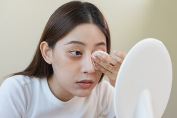 Wall Mural - Woman using cotton pad wipe to clean cosmetic on her face