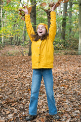 The joy of autumn. A teenage girl throws autumn leaves over her head in a park in November