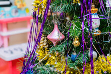 The Christmas Tree Is Decorated With Toys, A Yellow Garland And A Rain Of Foil