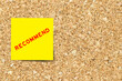 Yellow note paper with word recommend on cork board background with copy space