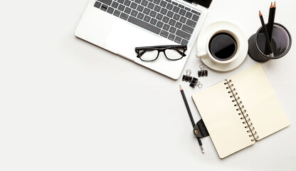 Flat lay, top view office table desk. Workspace with blank Laptop, office supplies, pencil, green leaf, and coffee cup on white background.