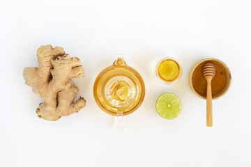 Wall Mural - Top view of a cup of tea with ginger root, lime, cinnamon and teapot on white background. Health drink concept.