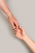 © Mercedes Fittipaldi - Imagen de primer plano de un hombre y una mujer dándose la mano sobre un fondo gris liso y aislado. Vista de frente y de cerca. Copy space. Formato vertical